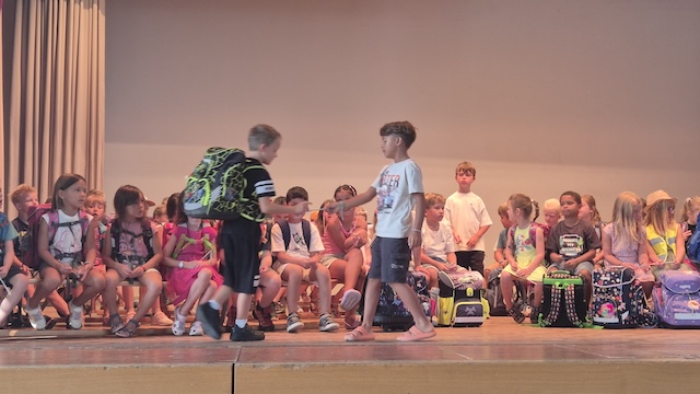 Gut aufgenommen mit «Gschenkli», sitzen die neuen Kinder der ersten Klassen mit ihren «Gspänli» und Lehrpersonen auf der Bühne. Foto: Monika Hauswirth